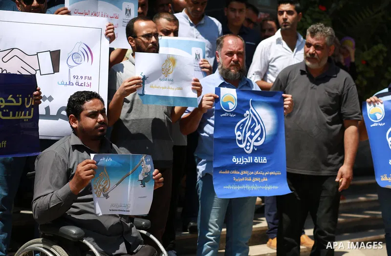 Palestinian journalists hold banners reading in Arabic ''Being a journalsit is not a crime'' and ''No to closing Al-Jazeera channel'' during a sit-in in solidarity with the al-Jazeera Arab satellite news broadcaster, in...