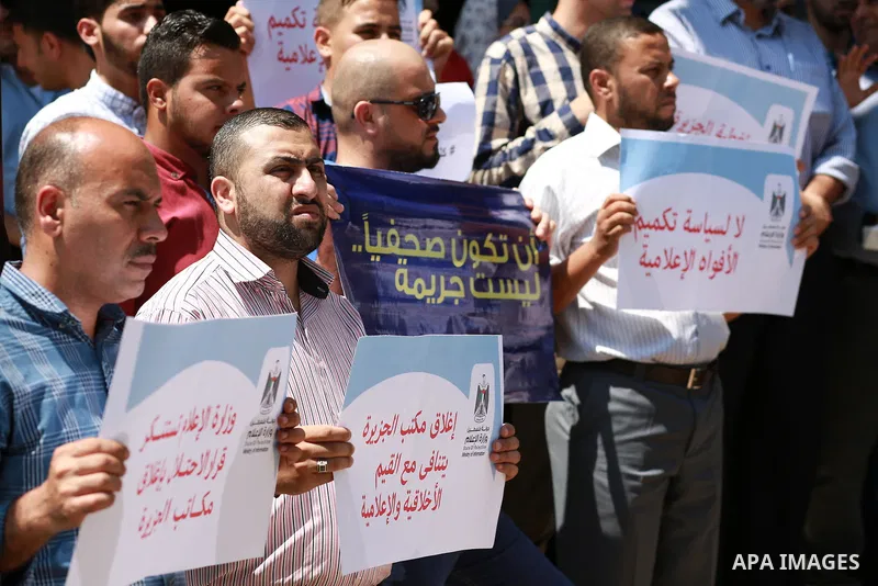 Palestinian journalists hold banners reading in Arabic ''Being a journalsit is not a crime'' and ''No to closing Al-Jazeera channel'' during a sit-in in solidarity with the al-Jazeera Arab satellite news broadcaster, in...