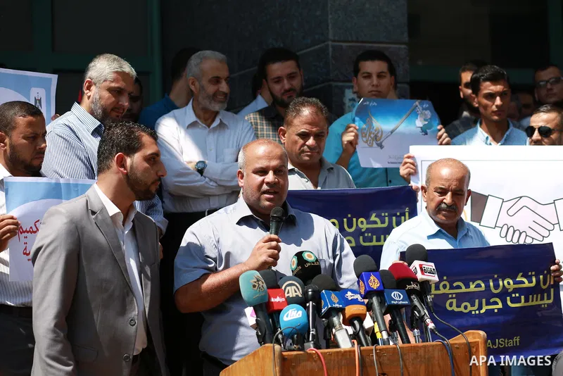 Palestinian journalists hold banners reading in Arabic ''Being a journalsit is not a crime'' and ''No to closing Al-Jazeera channel'' during a sit-in in solidarity with the al-Jazeera Arab satellite news broadcaster, in...