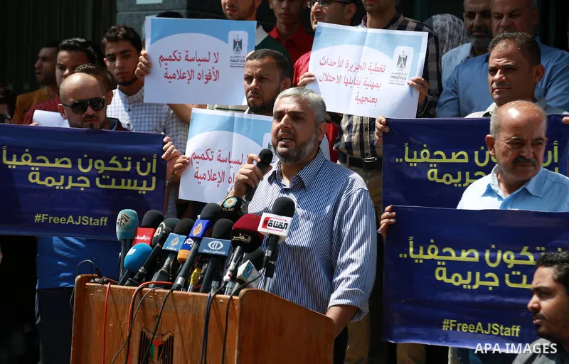Palestinian journalists hold banners reading in Arabic ''Being a journalsit is not a crime'' and ''No to closing Al-Jazeera channel'' during a sit-in in solidarity with the al-Jazeera Arab satellite news broadcaster, in...