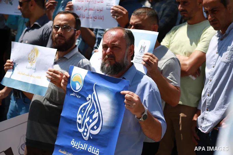 Palestinian journalists hold banners reading in Arabic ''Being a journalsit is not a crime'' and ''No to closing Al-Jazeera channel'' during a sit-in in solidarity with the al-Jazeera Arab satellite news broadcaster, in...