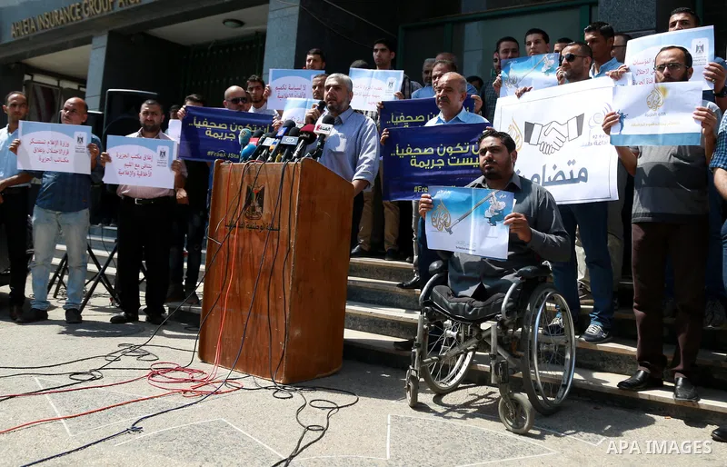 Palestinian journalists hold banners reading in Arabic ''Being a journalsit is not a crime'' and ''No to closing Al-Jazeera channel'' during a sit-in in solidarity with the al-Jazeera Arab satellite news broadcaster, in...
