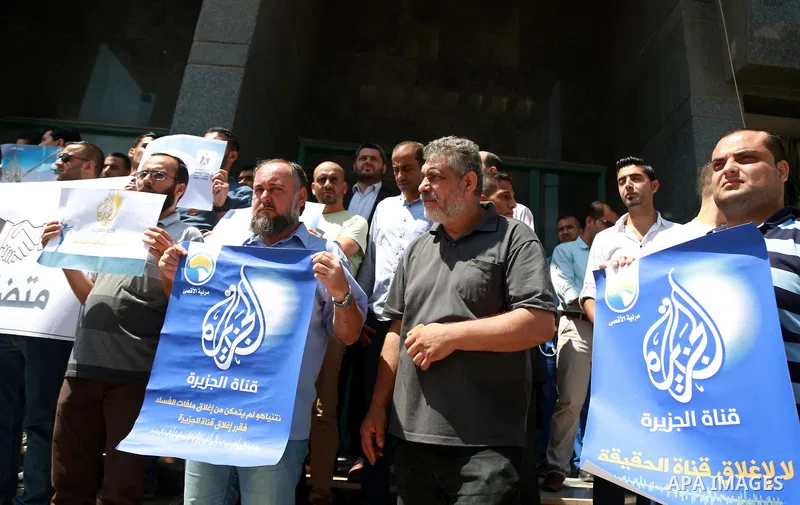 Palestinian journalists hold banners reading in Arabic ''Being a journalsit is not a crime'' and ''No to closing Al-Jazeera channel'' during a sit-in in solidarity with the al-Jazeera Arab satellite news broadcaster, in...