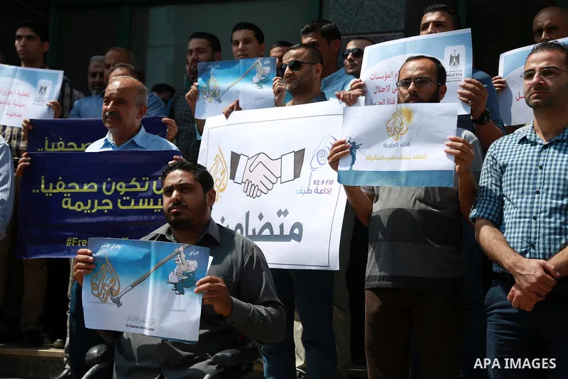 Palestinian journalists hold banners reading in Arabic ''Being a journalsit is not a crime'' and ''No to closing Al-Jazeera channel'' during a sit-in in solidarity with the al-Jazeera Arab satellite news broadcaster, in...