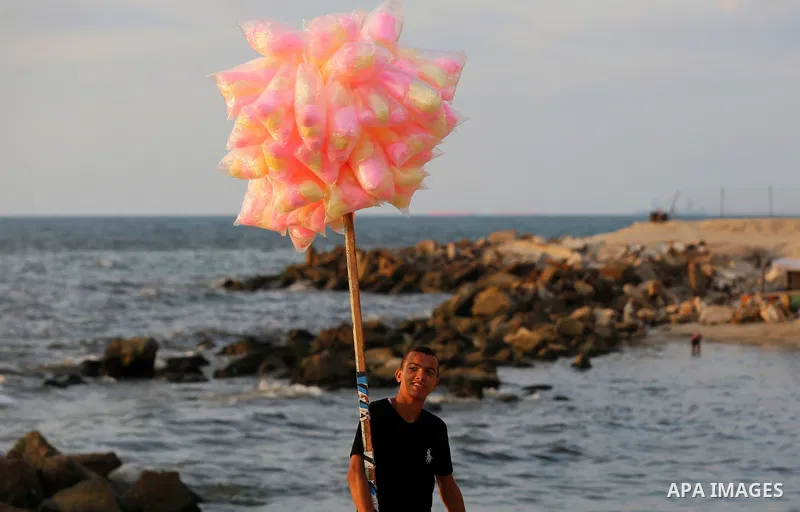 A Palestinian vendor sells sweets at the beach of the Mediterranean sea on the coast of Gaza city on August 9, 2017. Photo by Yasser Qudih