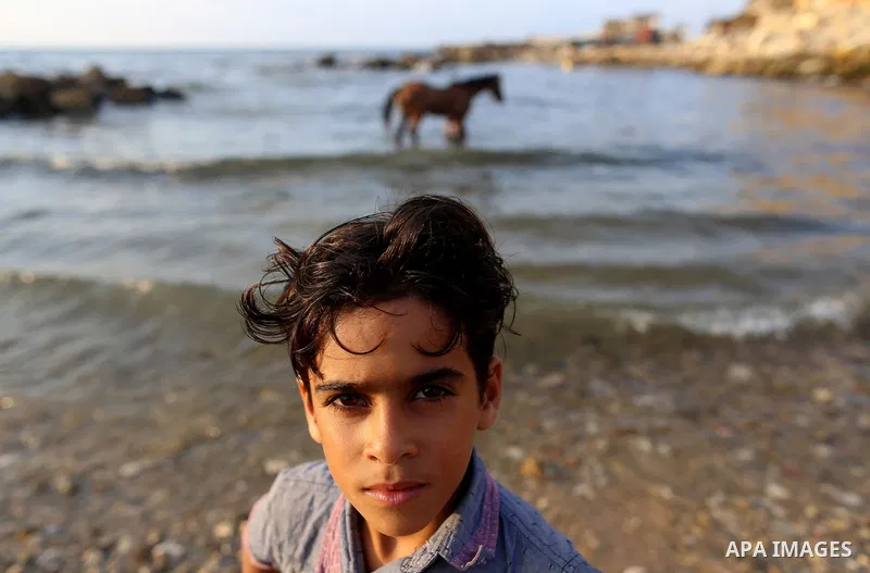 A Palestinian boy poses for a photo at the beach of the Mediterranean sea on the coast of Gaza city on August 9, 2017. Photo by Yasser Qudih