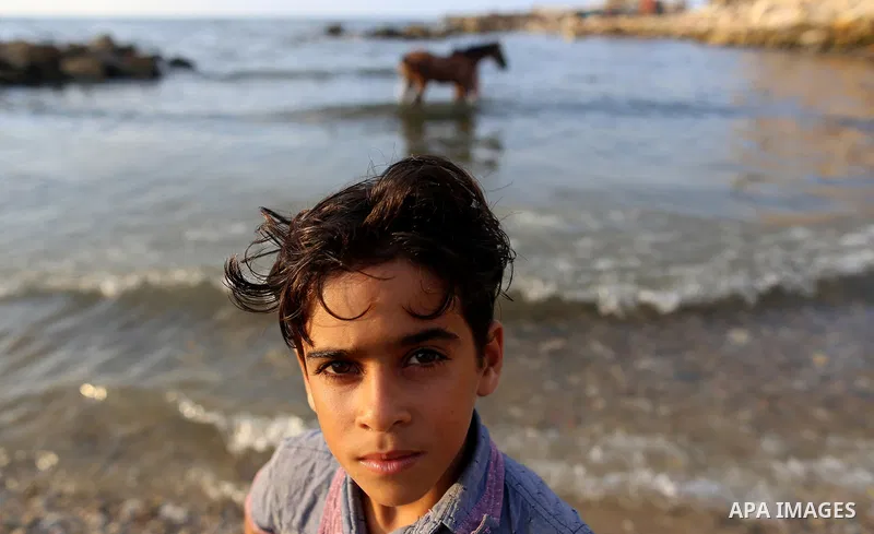 A Palestinian boy poses for a photo at the beach of the Mediterranean sea on the coast of Gaza city on August 9, 2017. Photo by Yasser Qudih