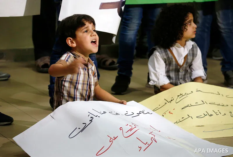 Palestinian children hold placards during a protest against the power and water crisis, at Hebron municipality, in the West Bank city of Hebron on August 9, 2017. Photo by Wisam Hashlamoun