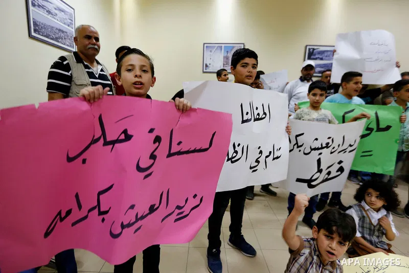 Palestinian children hold placards during a protest against the power and water crisis, at Hebron municipality, in the West Bank city of Hebron on August 9, 2017. Photo by Wisam Hashlamoun