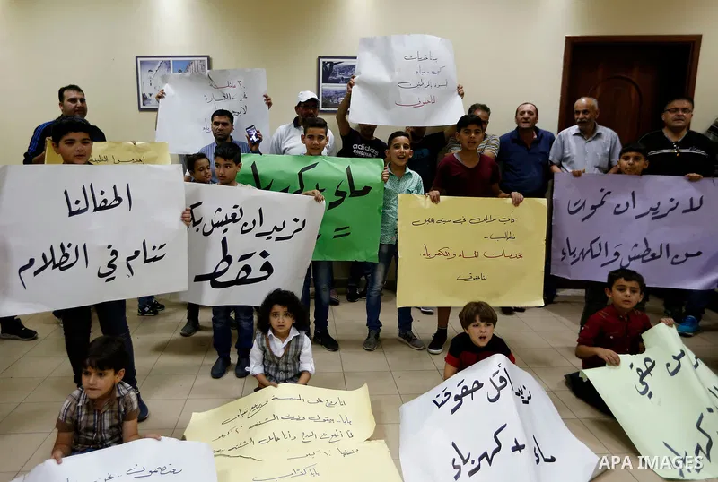 Palestinian children hold placards during a protest against the power and water crisis, at Hebron municipality, in the West Bank city of Hebron on August 9, 2017. Photo by Wisam Hashlamoun