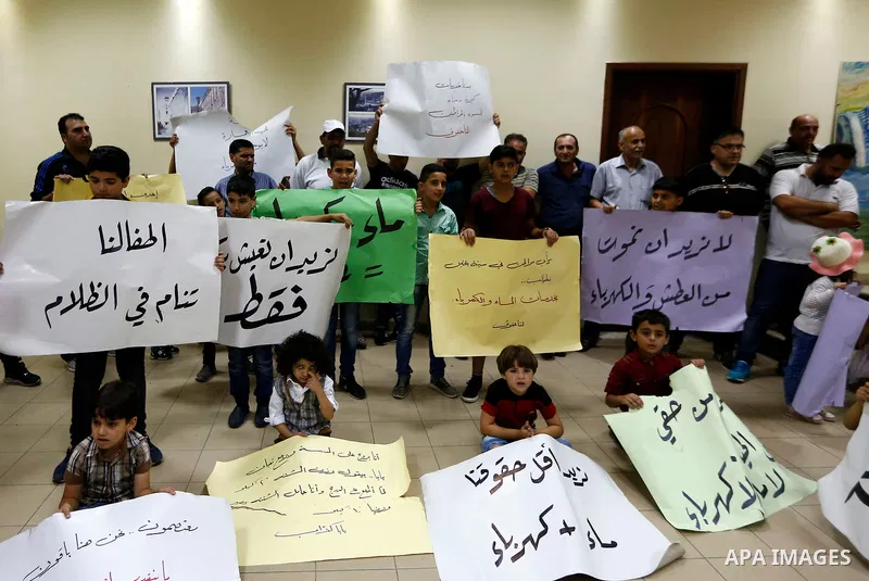 Palestinian children hold placards during a protest against the power and water crisis, at Hebron municipality, in the West Bank city of Hebron on August 9, 2017. Photo by Wisam Hashlamoun