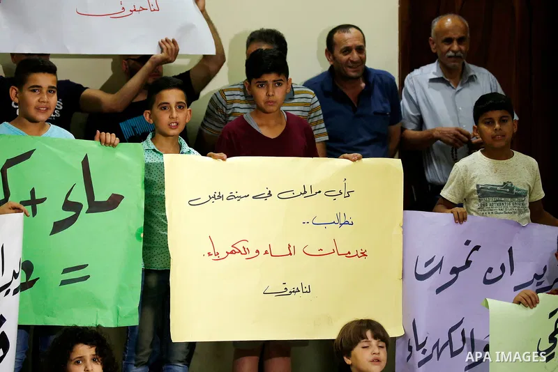 Palestinian children hold placards during a protest against the power and water crisis, at Hebron municipality, in the West Bank city of Hebron on August 9, 2017. Photo by Wisam Hashlamoun