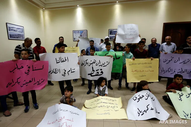 Palestinian children hold placards during a protest against the power and water crisis, at Hebron municipality, in the West Bank city of Hebron on August 9, 2017. Photo by Wisam Hashlamoun