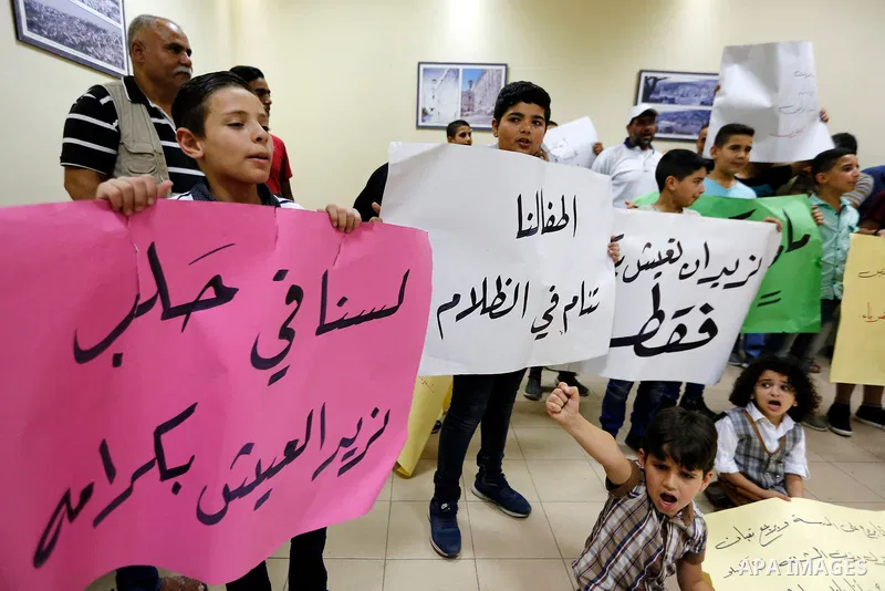Palestinian children hold placards during a protest against the power and water crisis, at Hebron municipality, in the West Bank city of Hebron on August 9, 2017. Photo by Wisam Hashlamoun