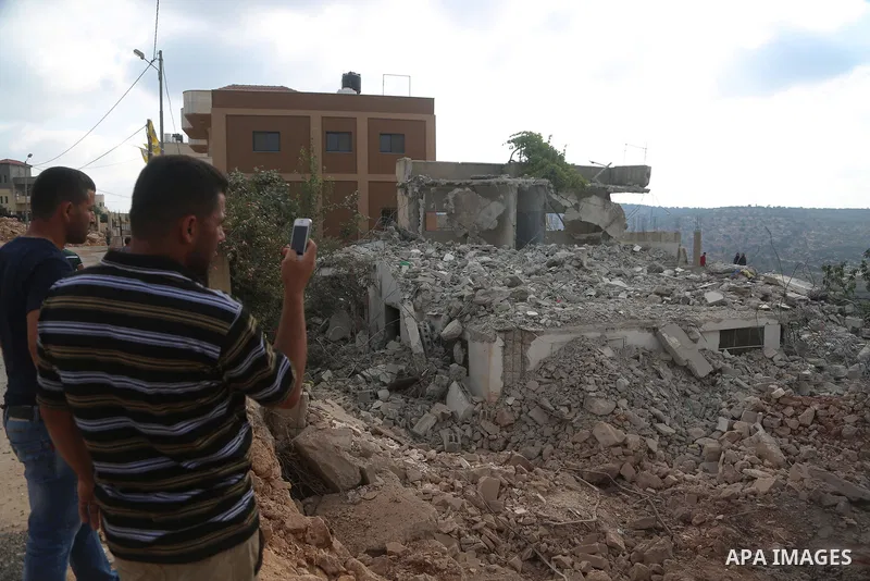 People gather around the remains of the house of a Palestinian assailant after it was demolished by Israeli troops in the West Bank village of Deir Abu Mashal, near Ramallah August 10, 2017. Photo by Shadi Hatem