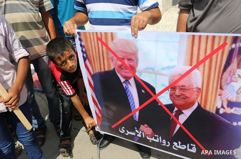 Palestinians hold a poster depicting Palestinian President Mahmoud Abbas during a protest against the blockade on Gaza strip and demanding their salaries in Gaza City on August 10, 2017. Photo by Ashraf Amra