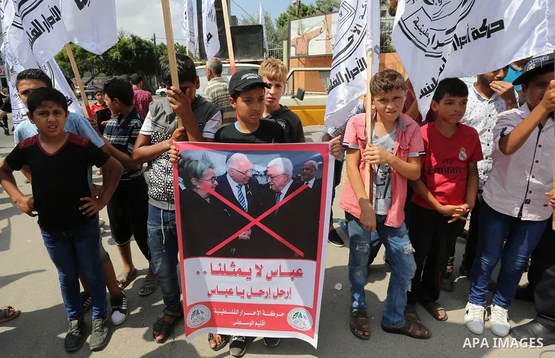 Palestinians hold a poster depicting Palestinian President Mahmoud Abbas during a protest against the blockade on Gaza strip and demanding their salaries in Gaza City on August 10, 2017. Photo by Ashraf Amra
