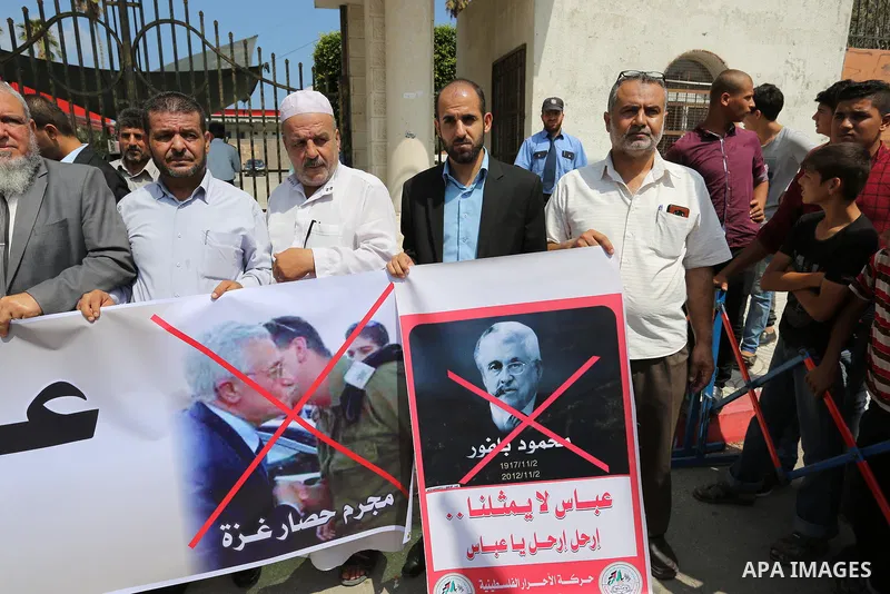 Palestinians hold a poster depicting Palestinian President Mahmoud Abbas during a protest against the blockade on Gaza strip and demanding their salaries in Gaza City on August 10, 2017. Photo by Ashraf Amra