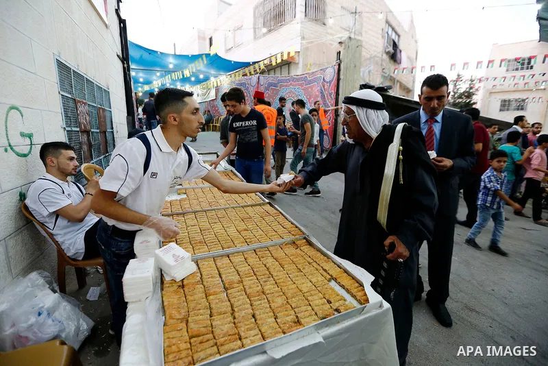A Palestinian man distributes sweets during a mass wedding for Thirty nine Palestinian grooms funded by Palestinian President Mahmoud Abbas in the West Bank village of Tafouh, east of Hebron, on August 10, 2017. Photo by...
