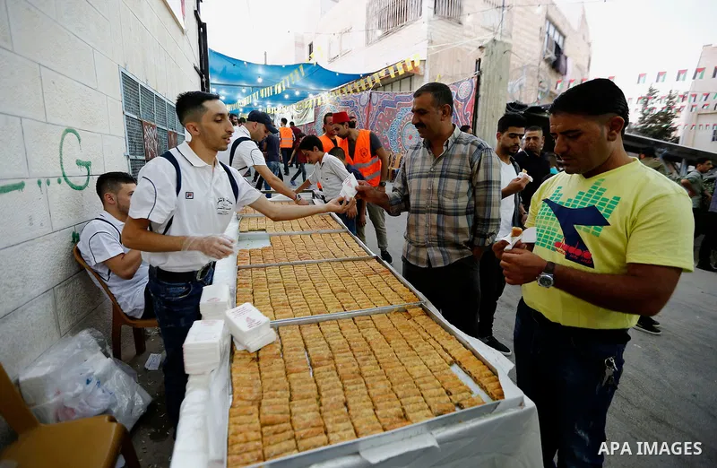 A Palestinian man distributes sweets during a mass wedding for Thirty nine Palestinian grooms funded by Palestinian President Mahmoud Abbas in the West Bank village of Tafouh, east of Hebron, on August 10, 2017. Photo by...