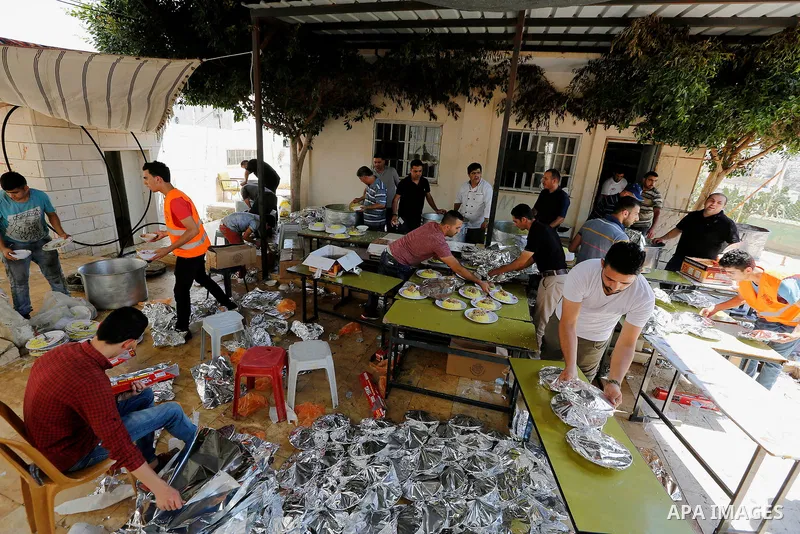 Palestinians prepare Lunch food during a mass wedding for Thirty nine Palestinian grooms funded by Palestinian President Mahmoud Abbas in the West Bank village of Tafouh, east of Hebron, on August 11, 2017. Photo by Wisa...