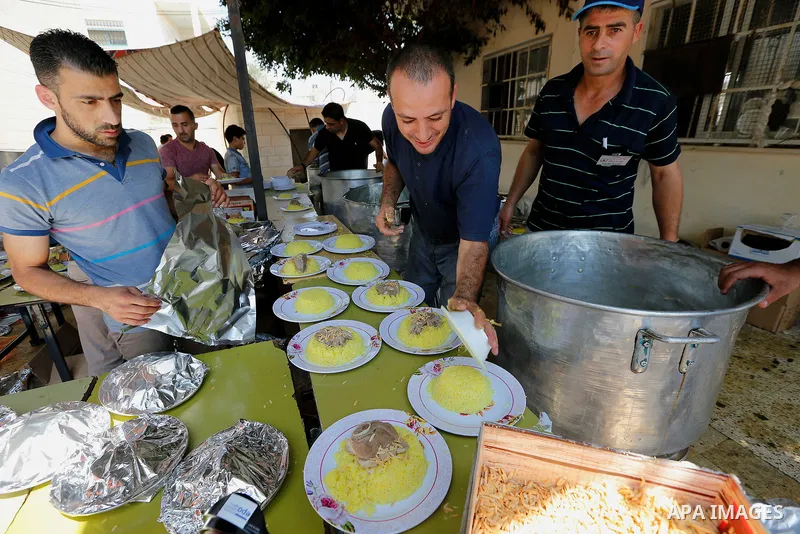 Palestinians prepare Lunch food during a mass wedding for Thirty nine Palestinian grooms funded by Palestinian President Mahmoud Abbas in the West Bank village of Tafouh, east of Hebron, on August 11, 2017. Photo by Wisa...