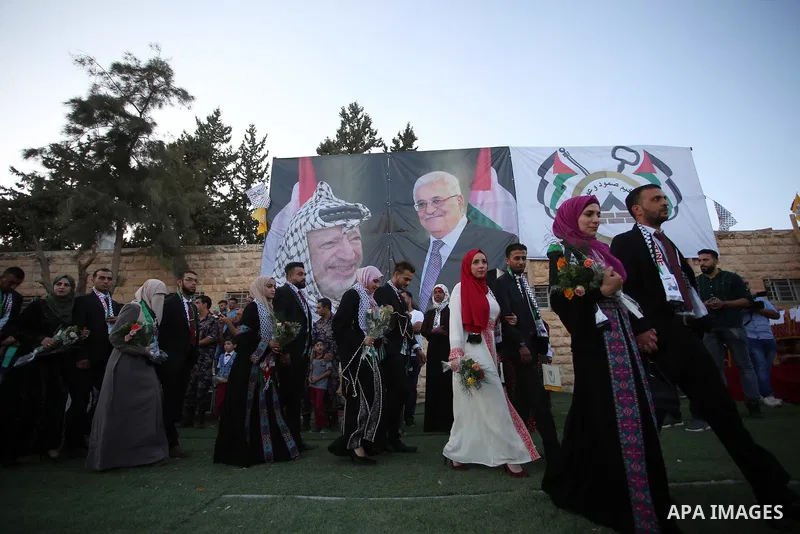 Palestinian 65 couples take part in a mass wedding ceremony funded by Palestinian President Mahmoud Abbas at Al-Fara refugee camp near the West Bank city of Nablus, on August 10, 2017. Photo by Ayman Ameen