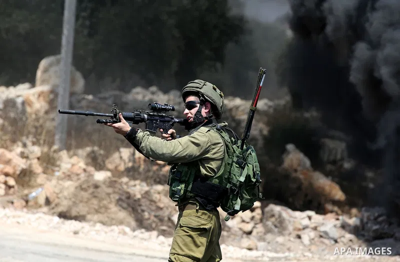 A member of Israeli security forces aims his weapon towards Palestinian protesters during clashes following a demonstration against the expropriation of Palestinian land by Israel in the village of Kfar Qaddum, near Nabl...