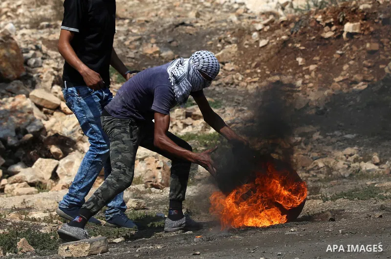 A Palestinian protester burns tires during clashes with Israeli security forces following a demonstration against the expropriation of Palestinian land by Israel in the village of Kfar Qaddum, near Nablus in the occupied...