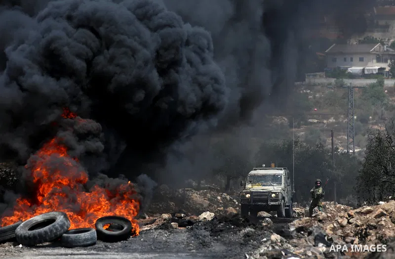 A member of Israeli security forces aims his weapon towards Palestinian protesters during clashes following a demonstration against the expropriation of Palestinian land by Israel in the village of Kfar Qaddum, near Nabl...