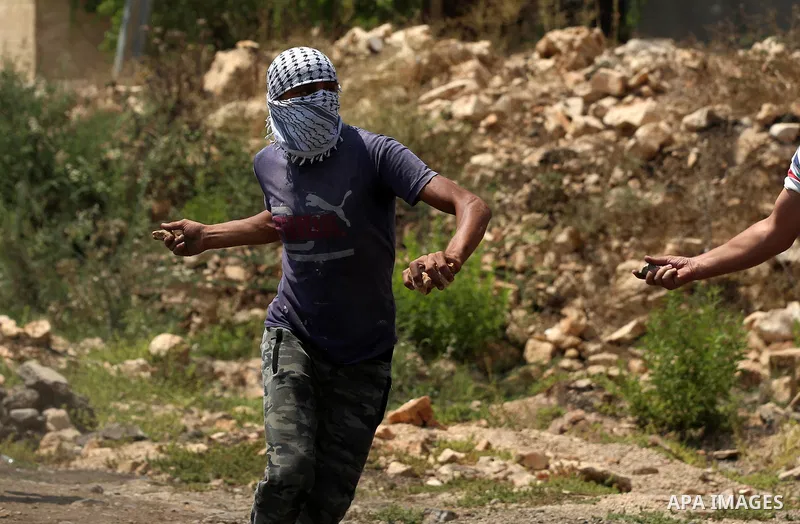 A Palestinian protester hurls stones towards Israeli security forces during clashes following a demonstration against the expropriation of Palestinian land by Israel in the village of Kfar Qaddum, near Nablus in the occu...