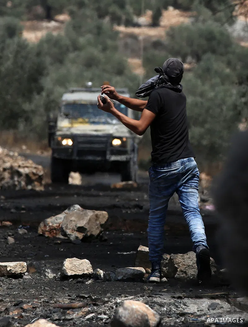 A Palestinian protester hurls stones towards Israeli security forces during clashes following a demonstration against the expropriation of Palestinian land by Israel in the village of Kfar Qaddum, near Nablus in the occu...