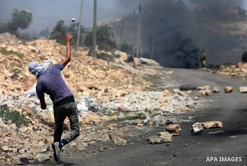A Palestinian protester hurls stones towards Israeli security forces during clashes following a demonstration against the expropriation of Palestinian land by Israel in the village of Kfar Qaddum, near Nablus in the occu...