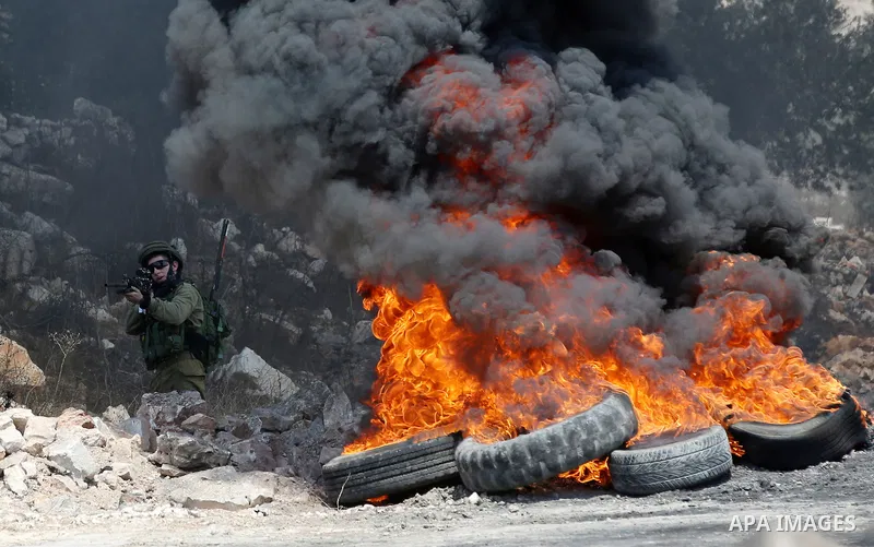 A member of Israeli security forces aims his weapon towards Palestinian protesters during clashes following a demonstration against the expropriation of Palestinian land by Israel in the village of Kfar Qaddum, near Nabl...