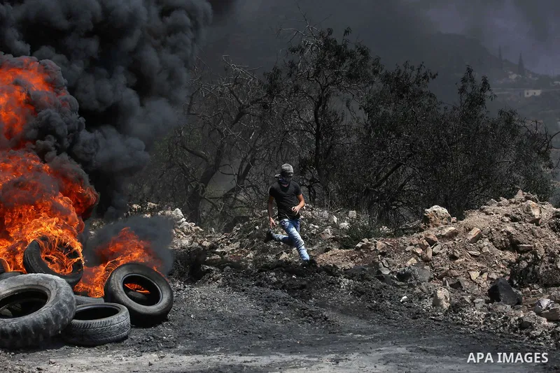 A Palestinian protester runs for cover during clashes with Israeli security forces following a demonstration against the expropriation of Palestinian land by Israel in the village of Kfar Qaddum, near Nablus in the occup...