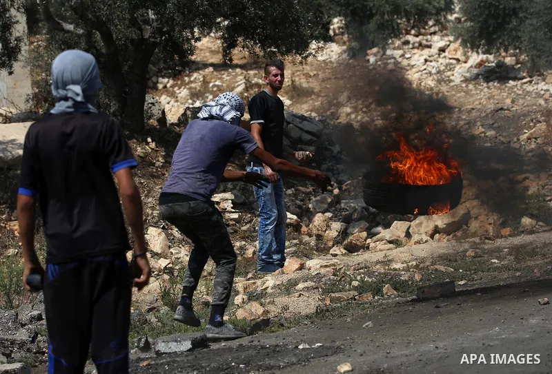 A Palestinian protester burns tires during clashes with Israeli security forces following a demonstration against the expropriation of Palestinian land by Israel in the village of Kfar Qaddum, near Nablus in the occupied...