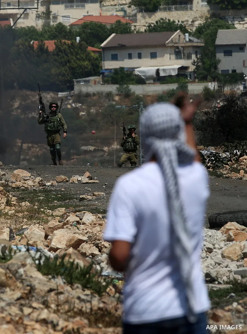 A Palestinian protester hurls stones towards Israeli security forces during clashes following a demonstration against the expropriation of Palestinian land by Israel in the village of Kfar Qaddum, near Nablus in the occu...