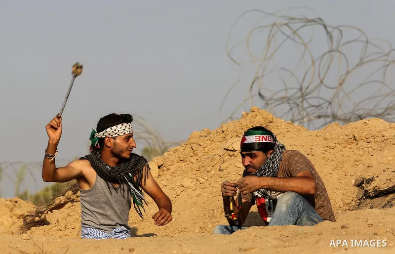 A Palestinian protester uses slingshots to hurl stones towards Israeli security forces during clashes near the border between Israel and Central Gaza Strip August 11, 2017. Photo by Ashraf Amra