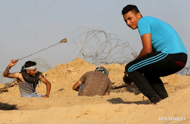 A Palestinian protester uses slingshots to hurl stones towards Israeli security forces during clashes near the border between Israel and Central Gaza Strip August 11, 2017. Photo by Ashraf Amra