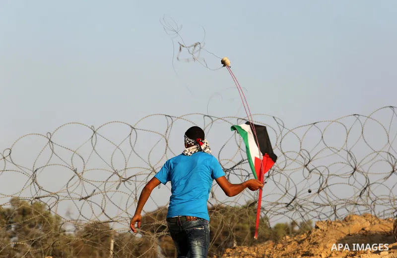 A Palestinian protester uses slingshots to hurl stones towards Israeli security forces during clashes near the border between Israel and Central Gaza Strip August 11, 2017. Photo by Ashraf Amra