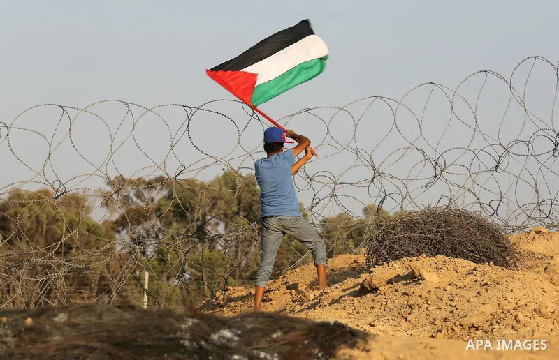 A Palestinian protester waves the national flag during clashes with Israeli security froces near the border between Israel and Central Gaza Strip August 11, 2017. Photo by Ashraf Amra