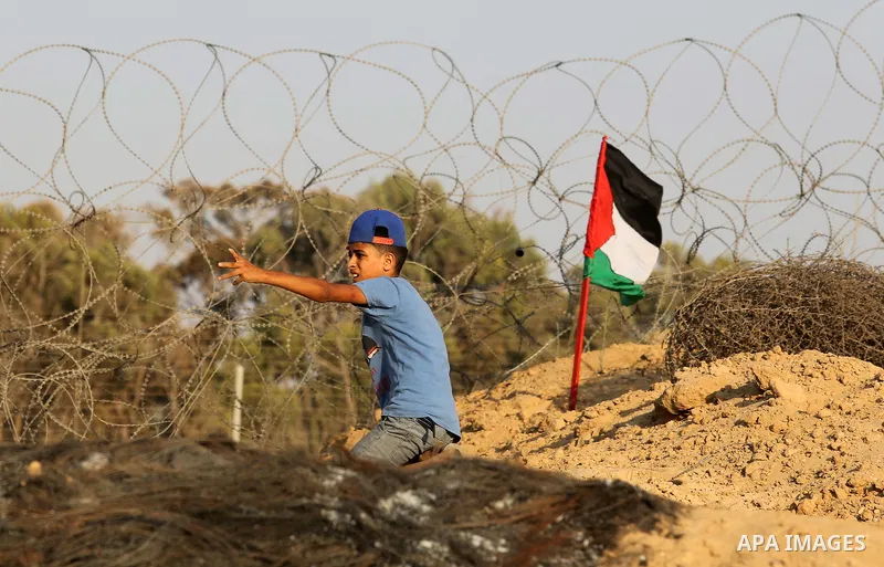A Palestinian protester hurls stones towards Israeli security forces during clashes near the border between Israel and Central Gaza Strip August 11, 2017. Photo by Ashraf Amra