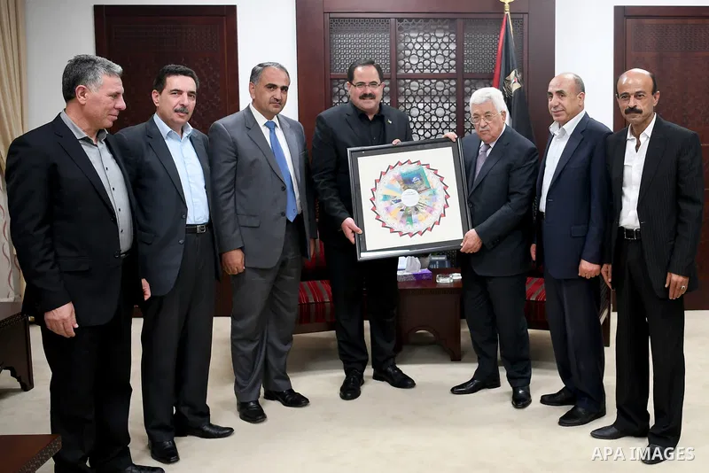 Palestinian President Mahmoud Abbas receives the first edition of the curriculum, at his headquarter, in the West Bank city of Ramallah, on August 12, 2017. Photo by Osama Falah