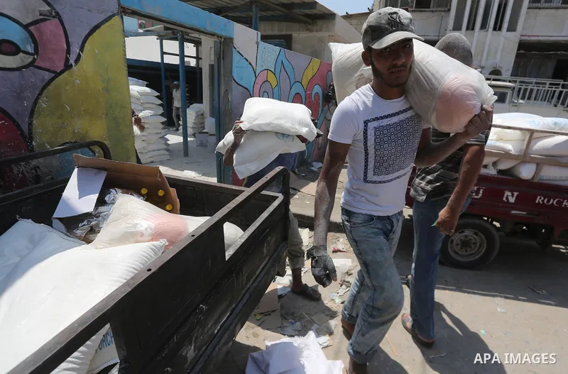 Palestinians receive their monthly food aid at a United Nations distribution center (UNRWA) in Gaza city on August 13, 2017. Photo by Mohammed Asad