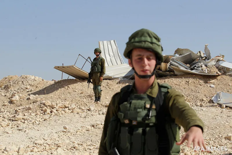 Israeli troops stand past the belongings of Palestinians as they arrive to demolish houses in the bedouin village of Khashm al-Daraj in the southern area of Yatta, south of the West Bank city of Hebron, on August 14, 201...