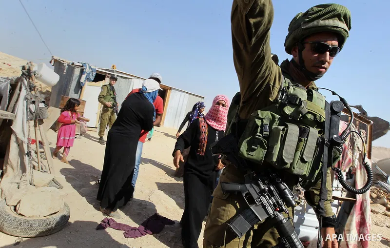 Israeli troops stand past the belongings of Palestinians as they arrive to demolish houses in the bedouin village of Khashm al-Daraj in the southern area of Yatta, south of the West Bank city of Hebron, on August 14, 201...