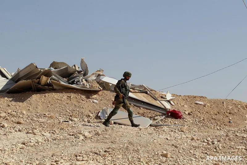 Israeli troops stand past the belongings of Palestinians as they arrive to demolish houses in the bedouin village of Khashm al-Daraj in the southern area of Yatta, south of the West Bank city of Hebron, on August 14, 201...