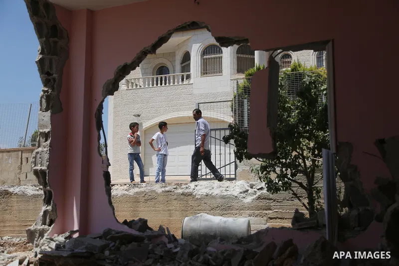 People check the remains of the house of a Palestinian man, who killed three Jewish residents of a nearby Israeli settlement, after it was demolished by Israeli authorities in the West Bank village of Kobar, near Ramalla...
