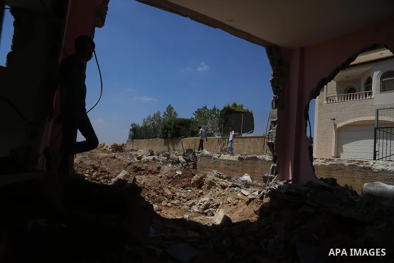 People check the remains of the house of a Palestinian man, who killed three Jewish residents of a nearby Israeli settlement, after it was demolished by Israeli authorities in the West Bank village of Kobar, near Ramalla...