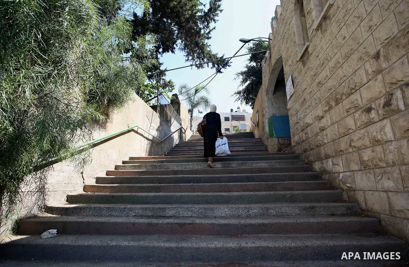 A Palestinian woman walks up stairs to reach the markets in the Old city of the West Bank city of Nablus on August 17, 2017. Nablus city is located between two mountains where hundreds of houses are built to face the inc...